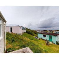 A traditional beach chalet vibe and outdoor seating with views toward St. Ives Bay